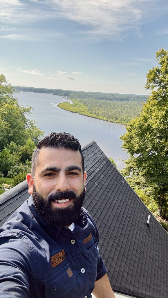 Image shows a home inspector (Juan Jimenez) comfortably perched on a roof.